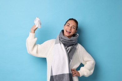 Smiling woman with tissue on light blue background