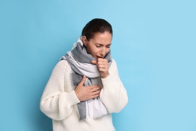 Photo of Sick woman coughing on light blue background, space for text. Cold symptoms