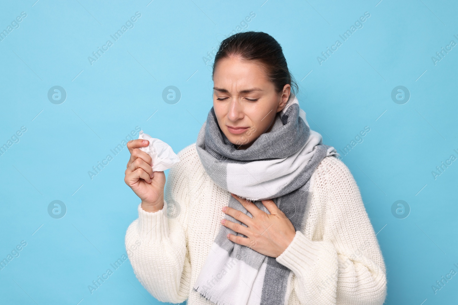 Photo of Sick woman with tissue on light blue background. Cold symptoms