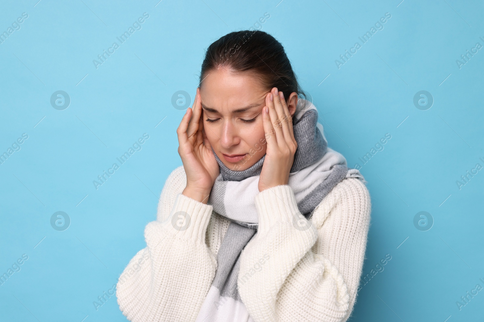 Photo of Sick woman suffering from cold symptoms on light blue background