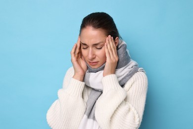 Photo of Sick woman suffering from cold symptoms on light blue background