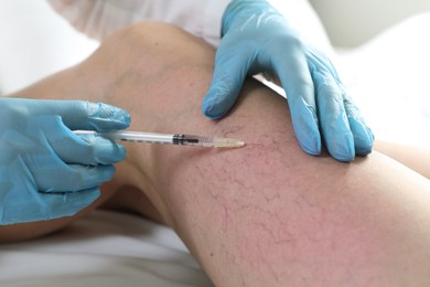 Photo of Varicose veins treatment. Doctor giving injection to patient indoors, closeup