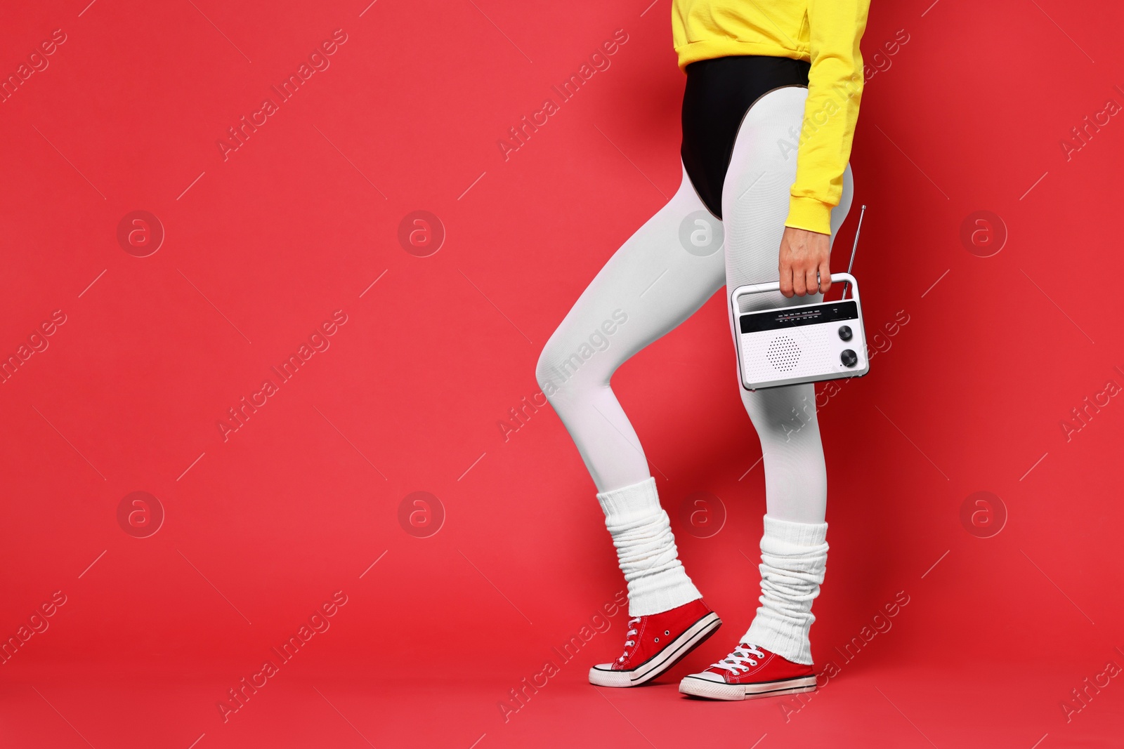 Photo of Aerobics. Woman in sportswear holding radio receiver on red background, closeup. Space for text