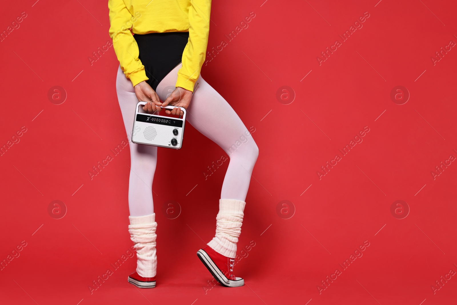 Photo of Aerobics. Woman in sportswear holding radio receiver on red background, closeup. Space for text