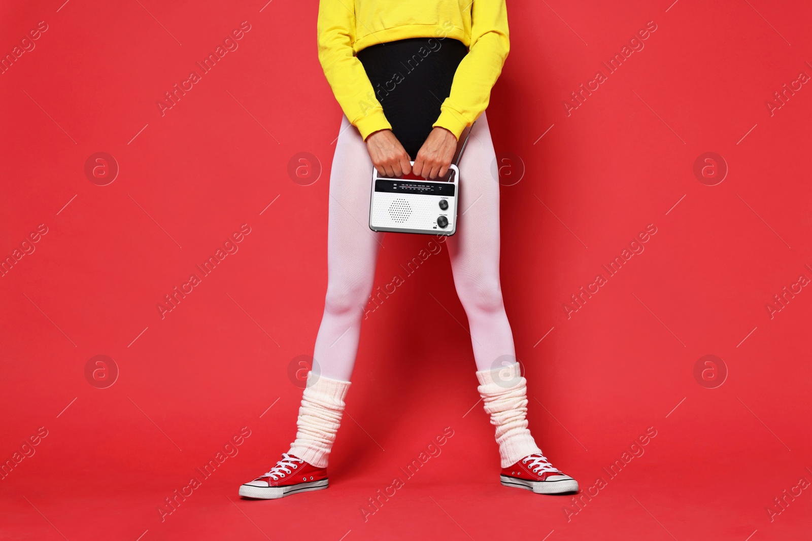 Photo of Aerobics. Woman in sportswear holding radio receiver on red background, closeup