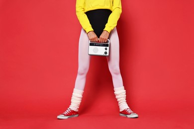 Photo of Aerobics. Woman in sportswear holding radio receiver on red background, closeup