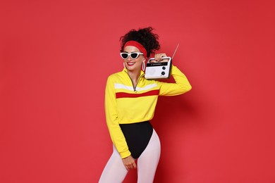 Photo of Aerobics. Woman in sportswear holding radio receiver on red background