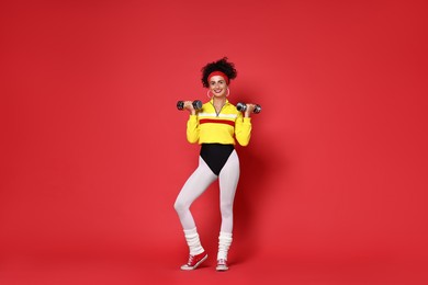 Woman doing aerobic exercise with dumbbells on red background