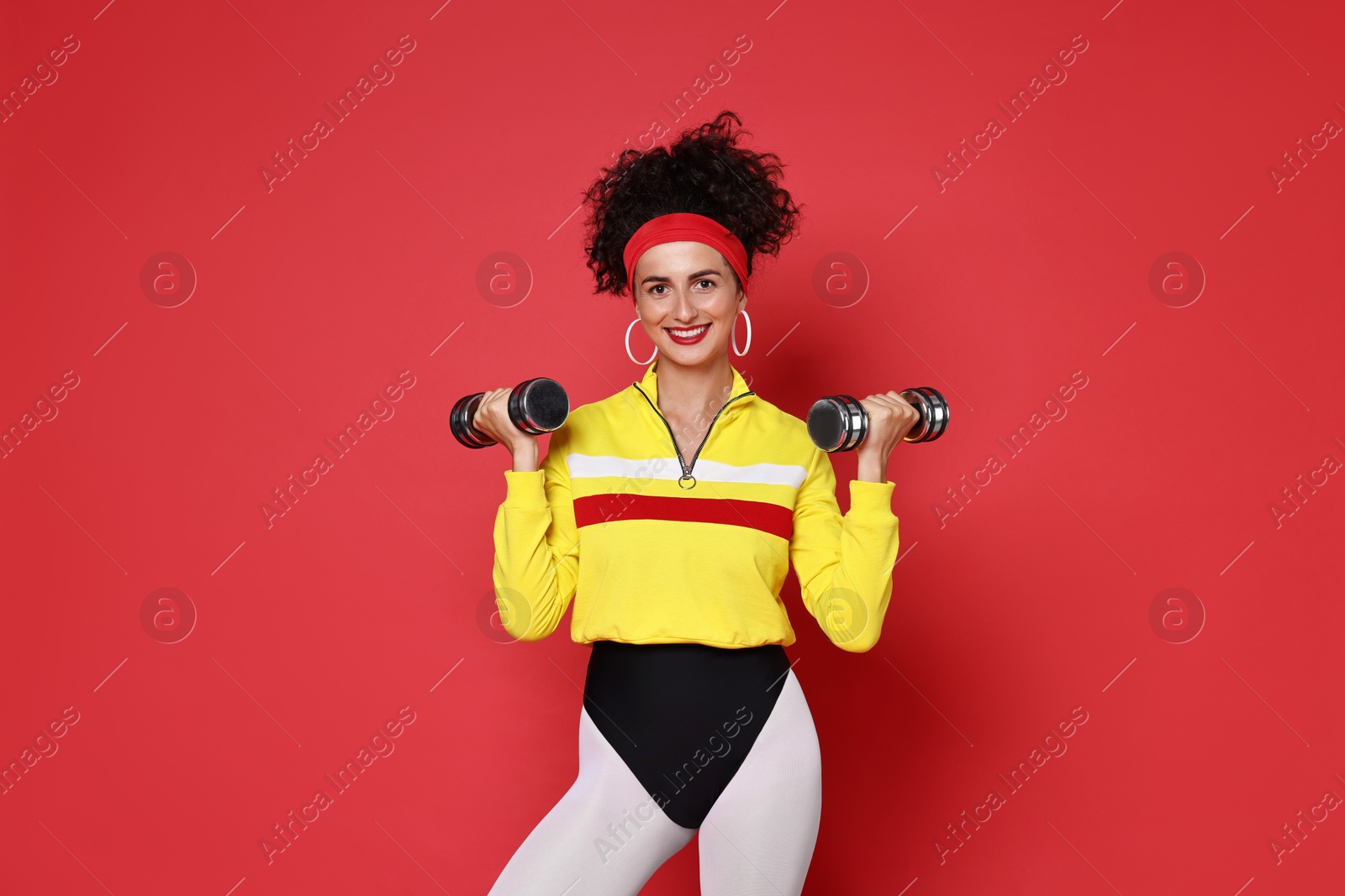 Photo of Woman doing aerobic exercise with dumbbells on red background