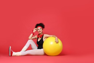 Photo of Aerobics. Happy woman with fitness ball on red background