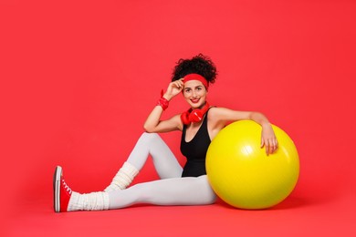 Aerobics. Happy woman with fitness ball on red background