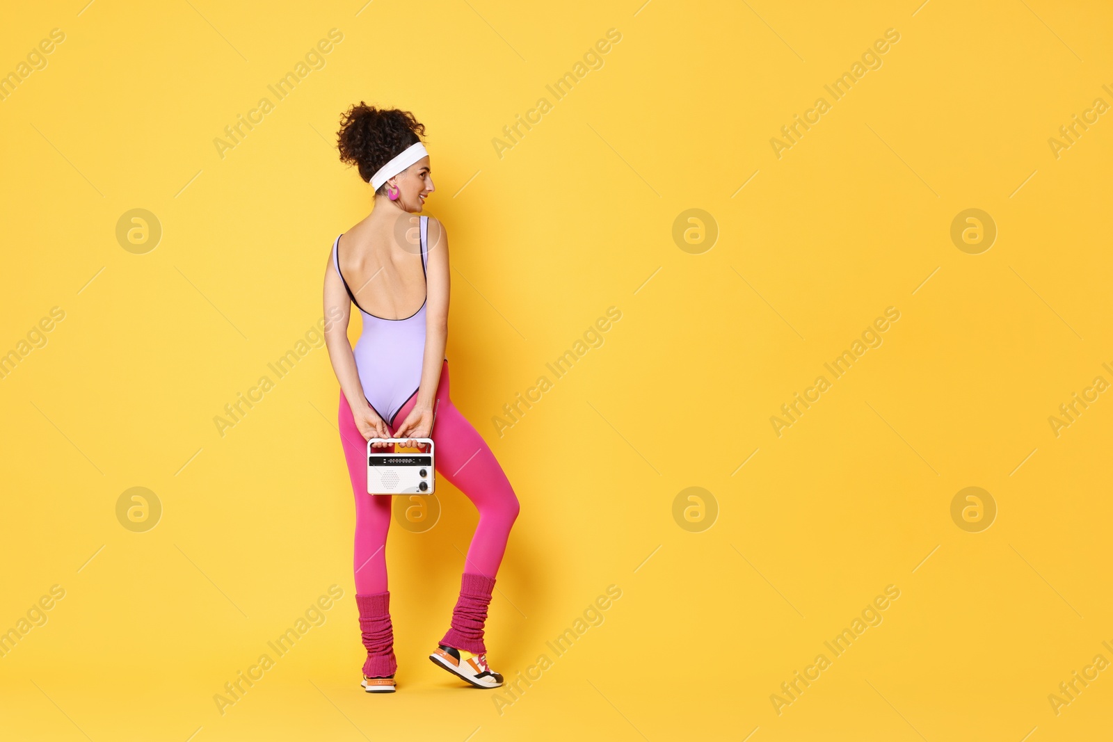 Photo of Aerobics. Woman with radio receiver on orange background