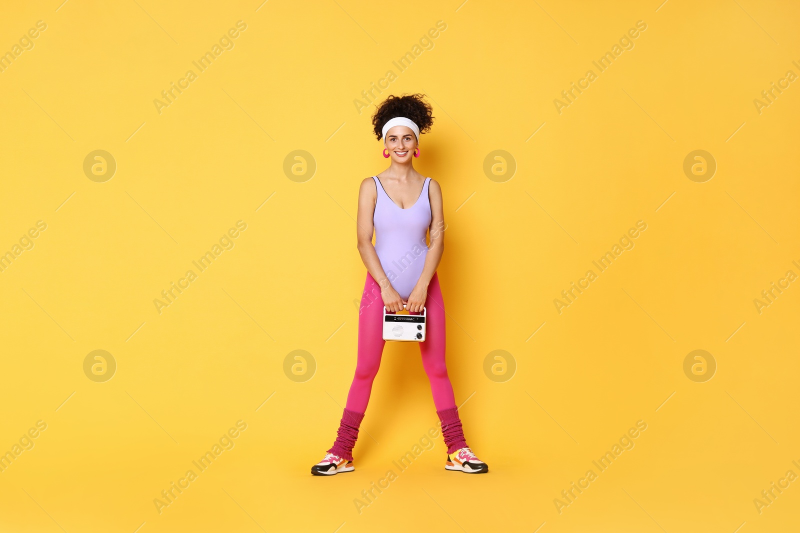 Photo of Aerobics. Woman with radio receiver on orange background