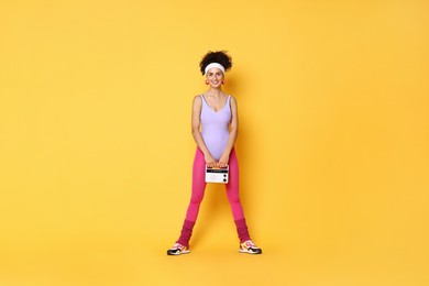 Photo of Aerobics. Woman with radio receiver on orange background