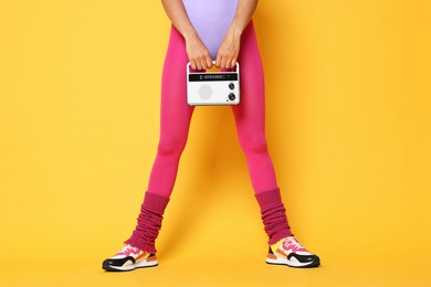 Photo of Aerobics. Woman with radio receiver on orange background, closeup