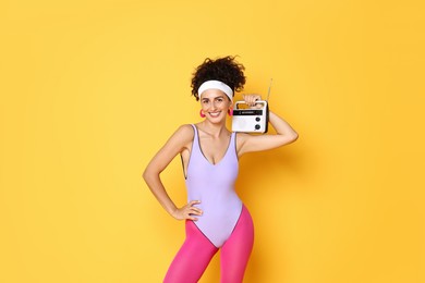 Aerobics. Woman with radio receiver on orange background