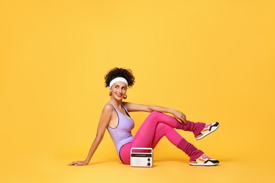 Aerobics. Woman with radio receiver on orange background