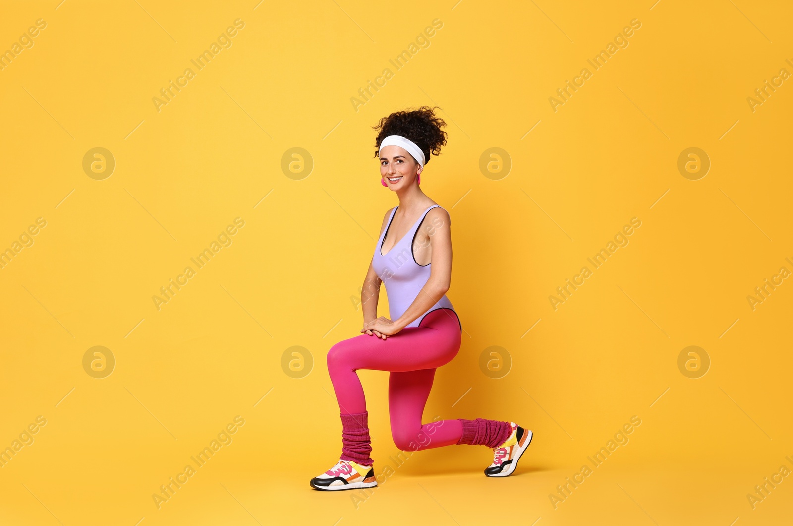 Photo of Happy woman doing aerobic exercise on orange background