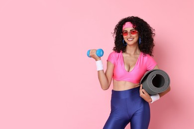 Photo of Aerobics. Happy woman with dumbbell and fitness mat on pink background, space for text