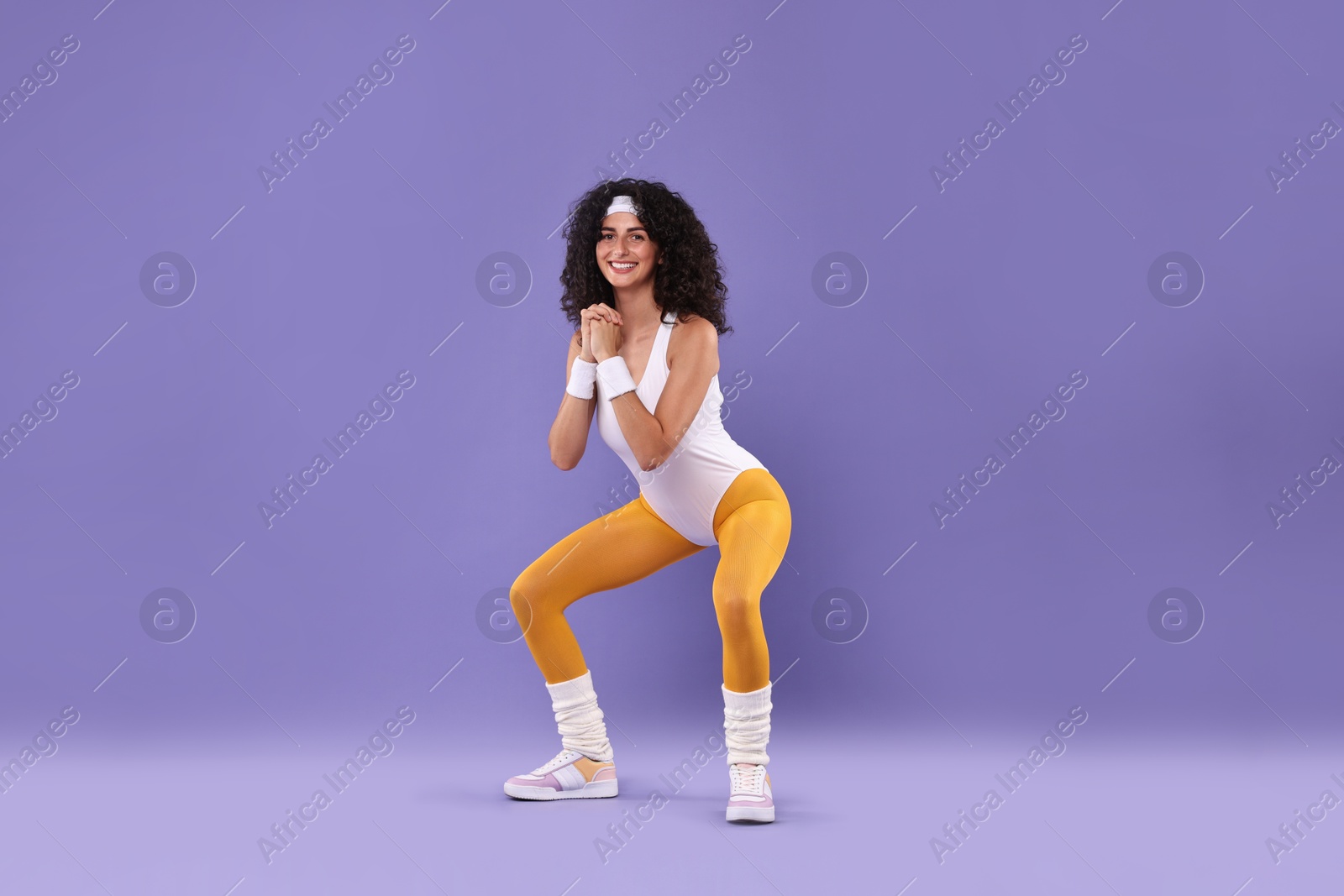 Photo of Happy woman doing aerobic exercise on purple background