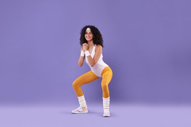 Happy woman doing aerobic exercise on purple background