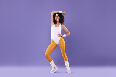 Happy woman in sportswear on purple background