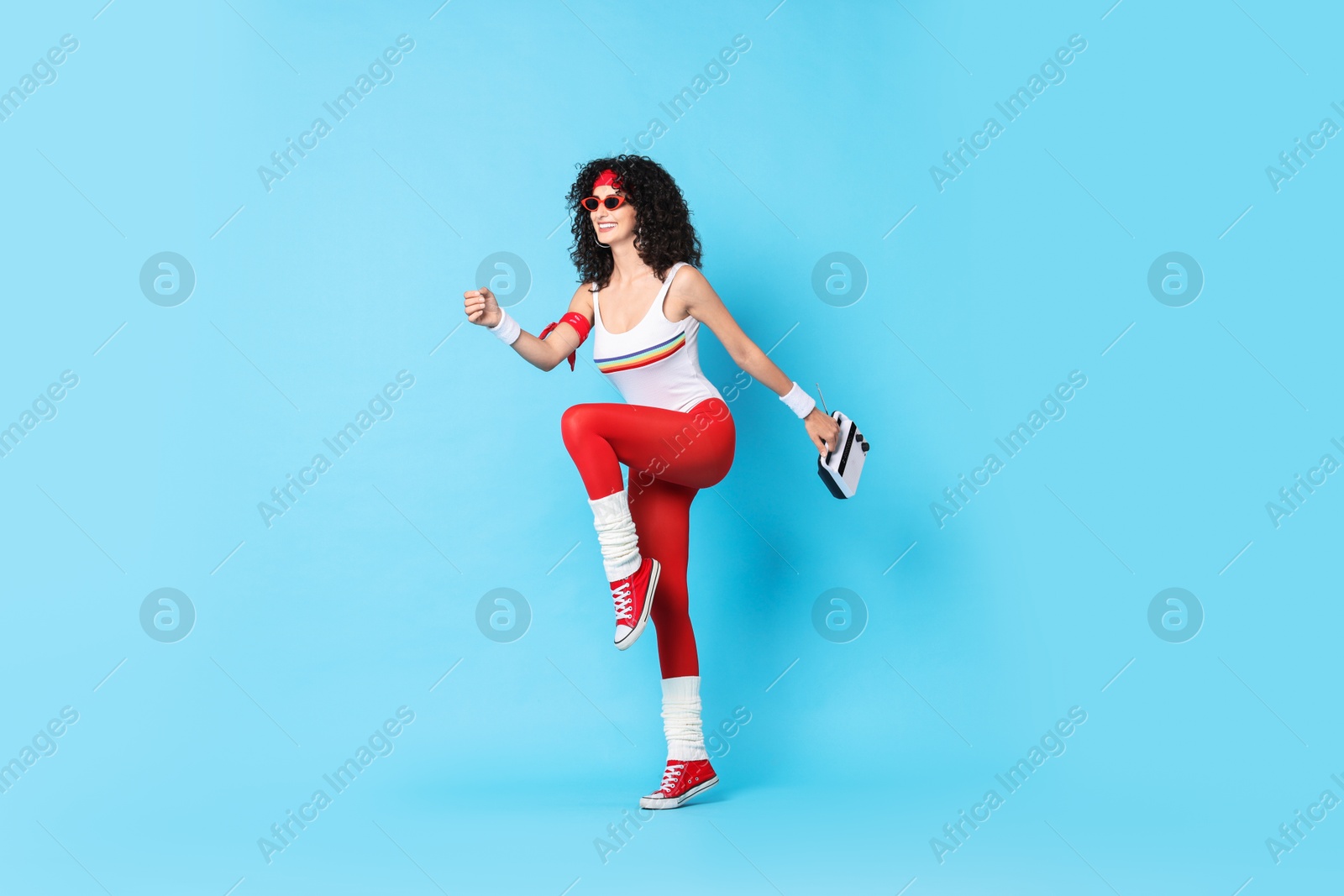 Photo of Happy woman with radio receiver doing aerobic exercise on light blue background