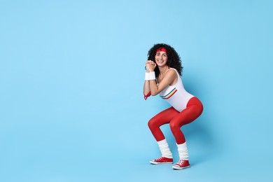 Woman doing aerobic exercise on light blue background, space for text