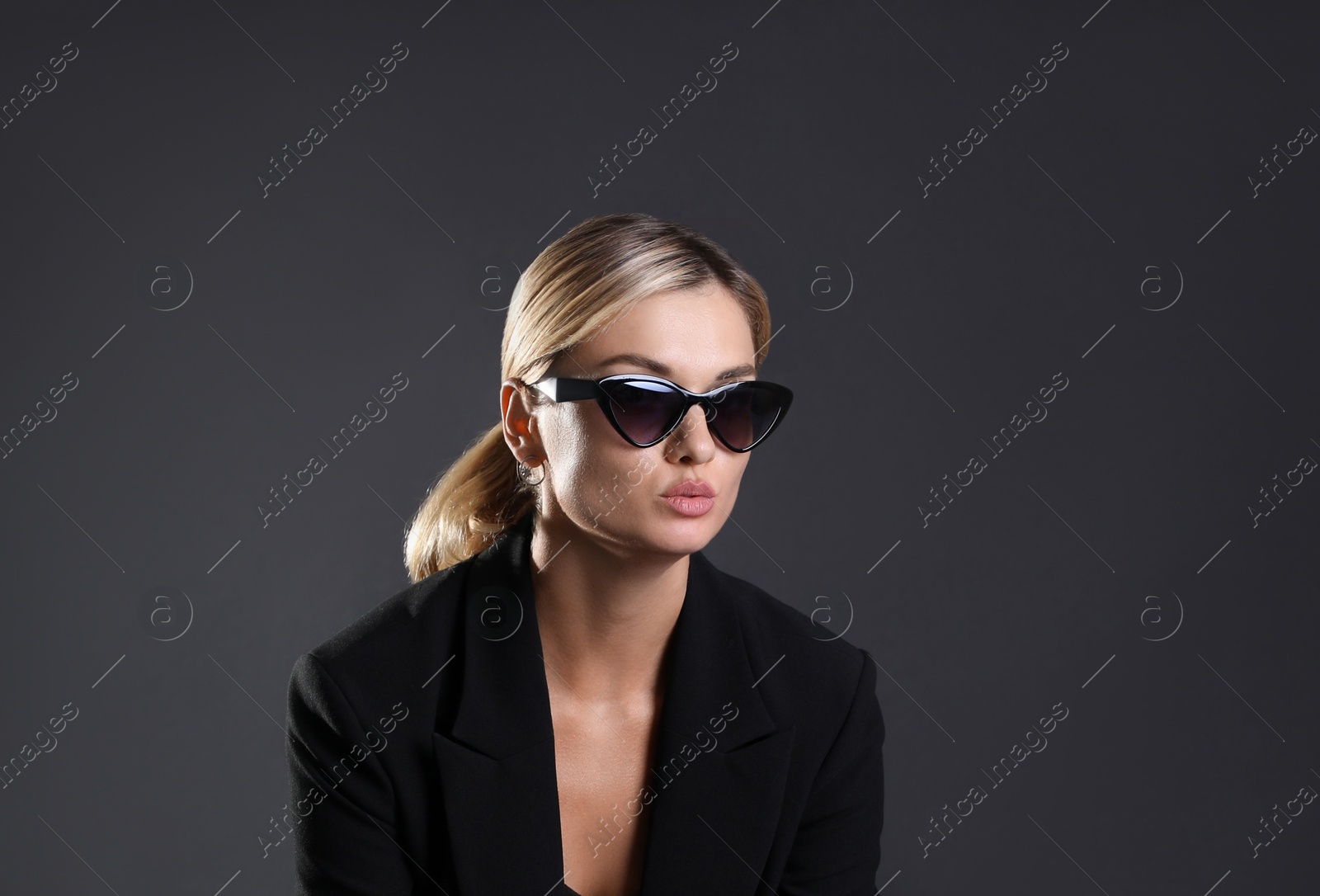 Photo of Beautiful woman in stylish suit sitting on chair against black background