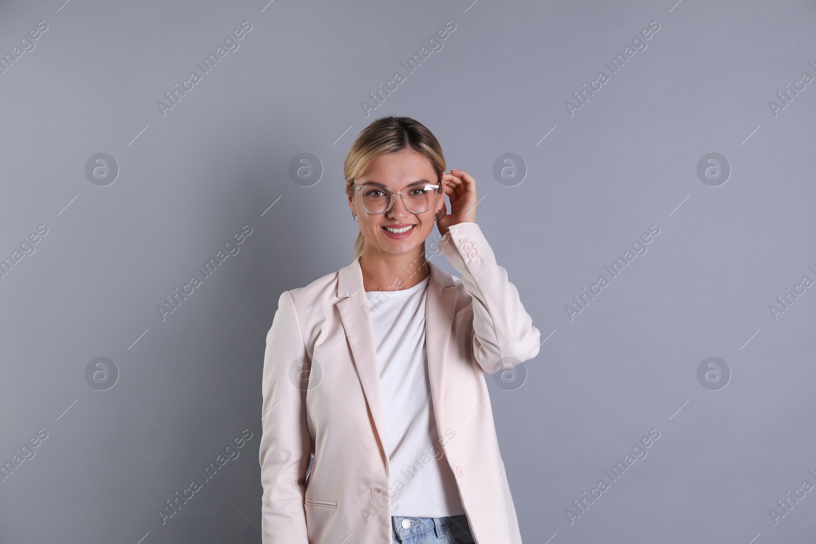 Photo of Beautiful woman in stylish jacket and glasses on grey background