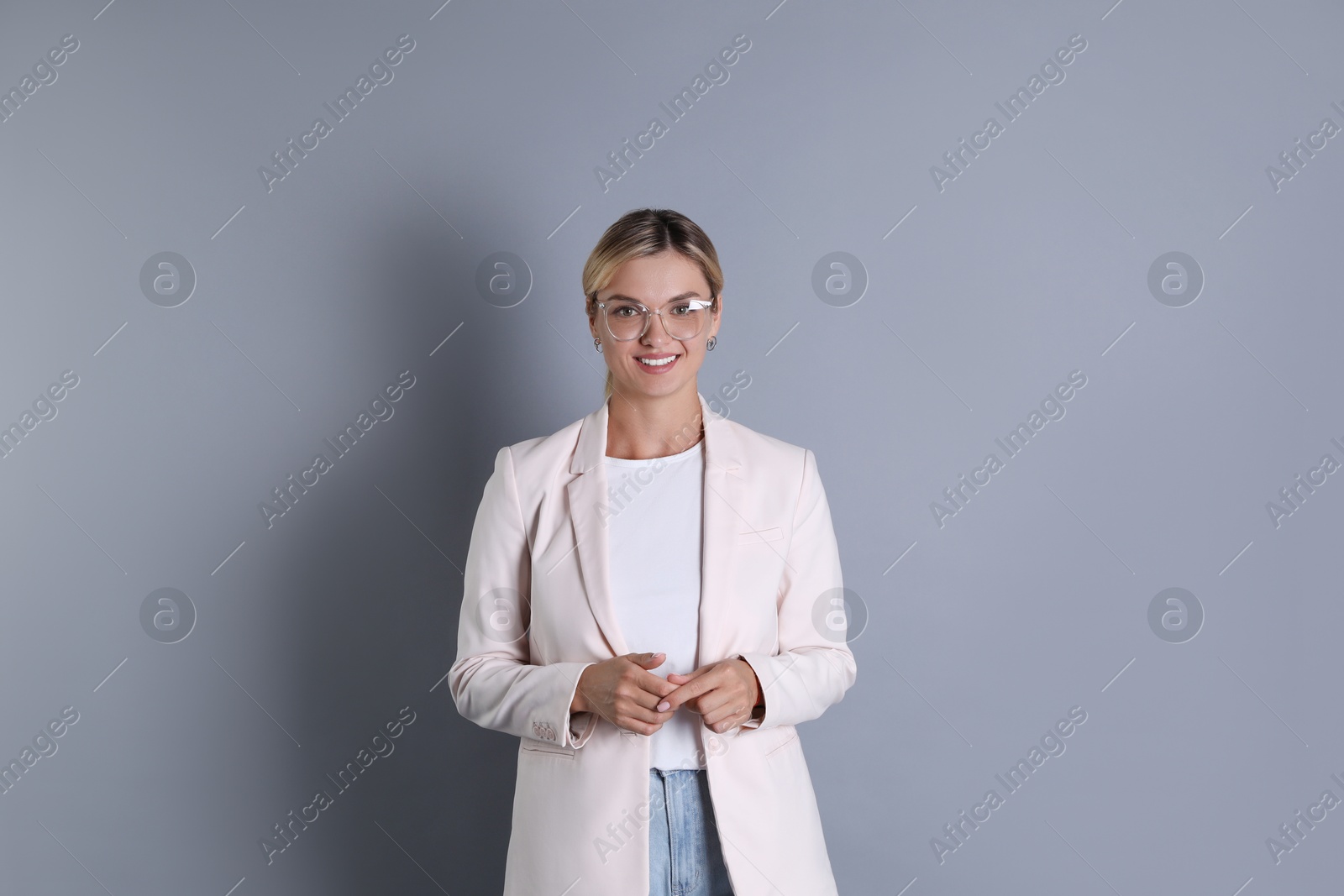 Photo of Beautiful woman in stylish jacket and glasses on grey background