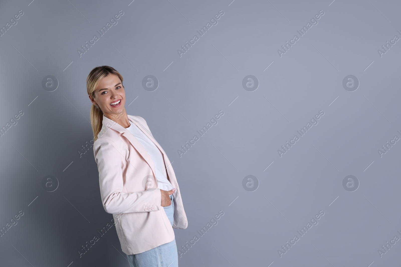 Photo of Beautiful woman in stylish jacket and glasses on grey background, space for text