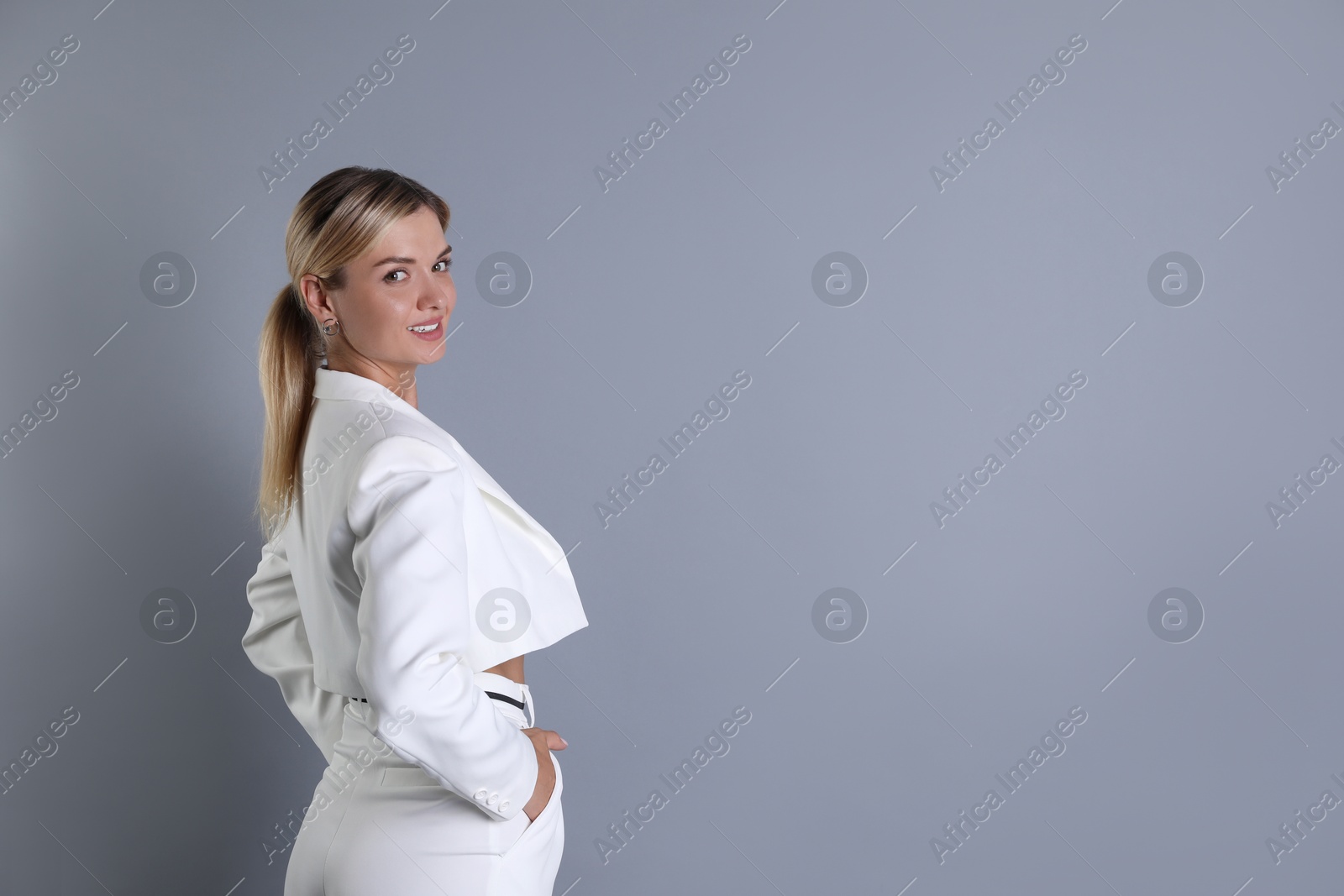 Photo of Beautiful woman in stylish white suit on grey background, space for text