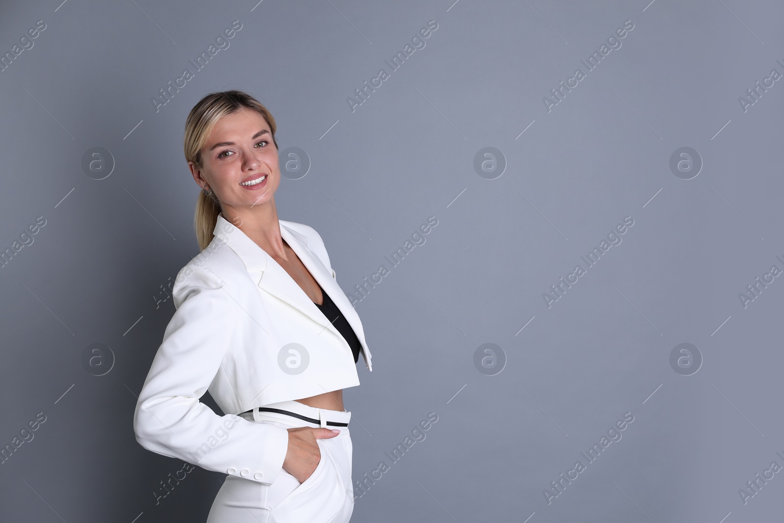 Photo of Beautiful woman in stylish white suit on grey background, space for text