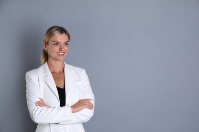 Photo of Beautiful woman in stylish white suit on grey background, space for text