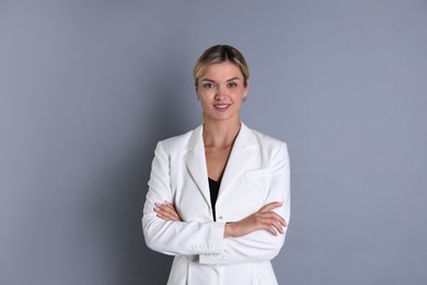 Beautiful woman in stylish white suit on grey background