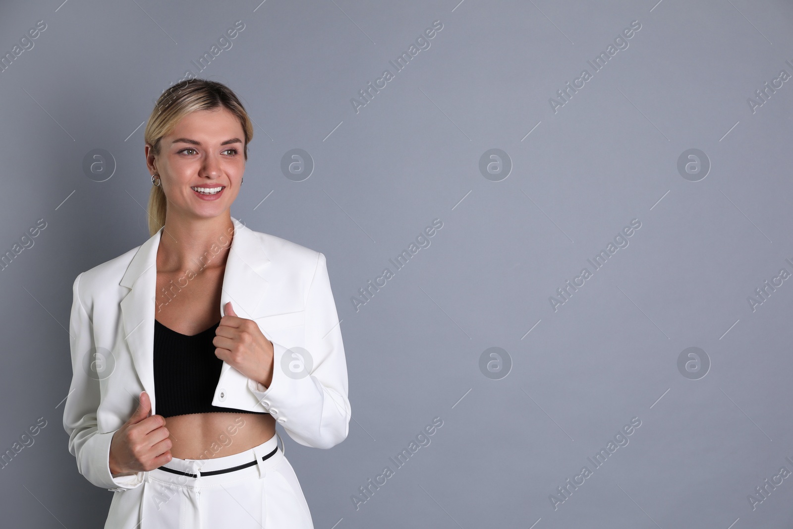 Photo of Beautiful woman in stylish white suit on grey background, space for text