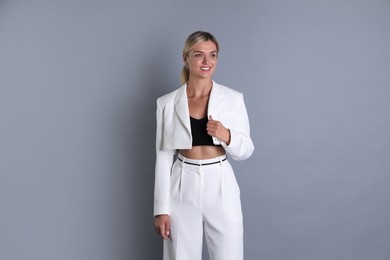 Beautiful woman in stylish white suit on grey background