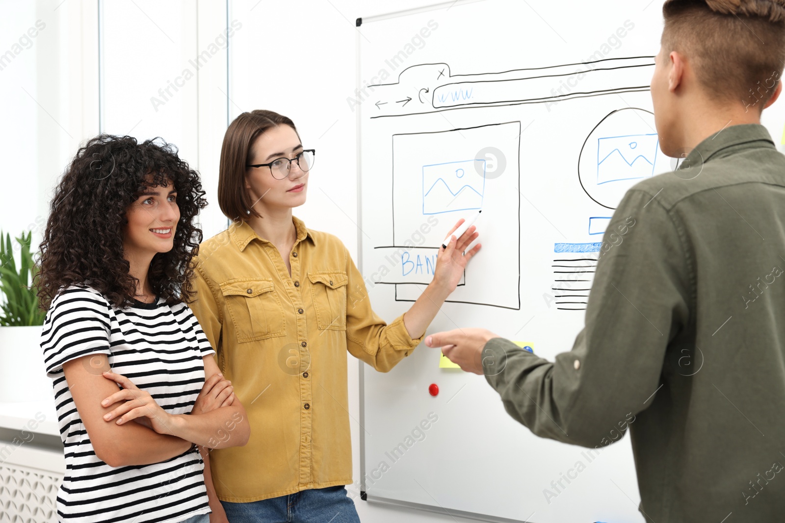 Photo of Developing UI design. People drawing website wireframe on whiteboard indoors