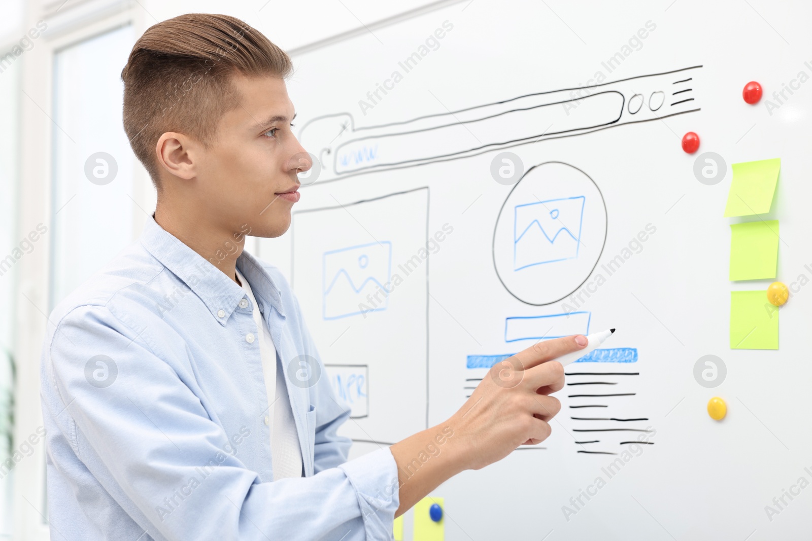 Photo of Developing UI design. Man drawing website wireframe on whiteboard indoors