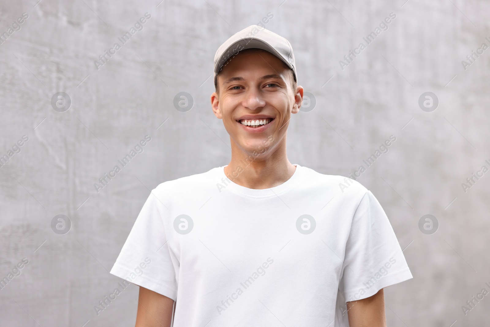 Photo of Portrait of smiling man in baseball cap near light wall