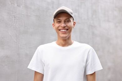 Portrait of smiling man in baseball cap near light wall