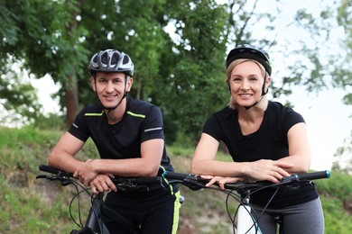 Photo of Happy couple with bicycles in park, low angle view