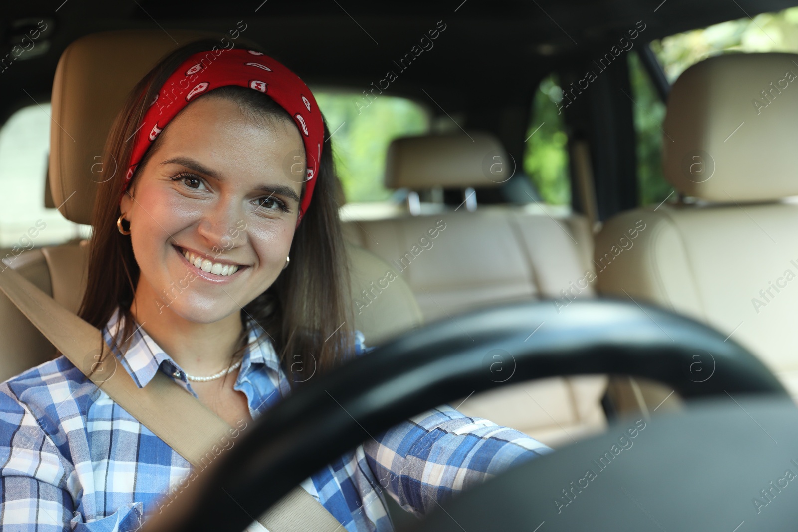 Photo of Smiling woman holding steering wheel while driving car, view from through windshield