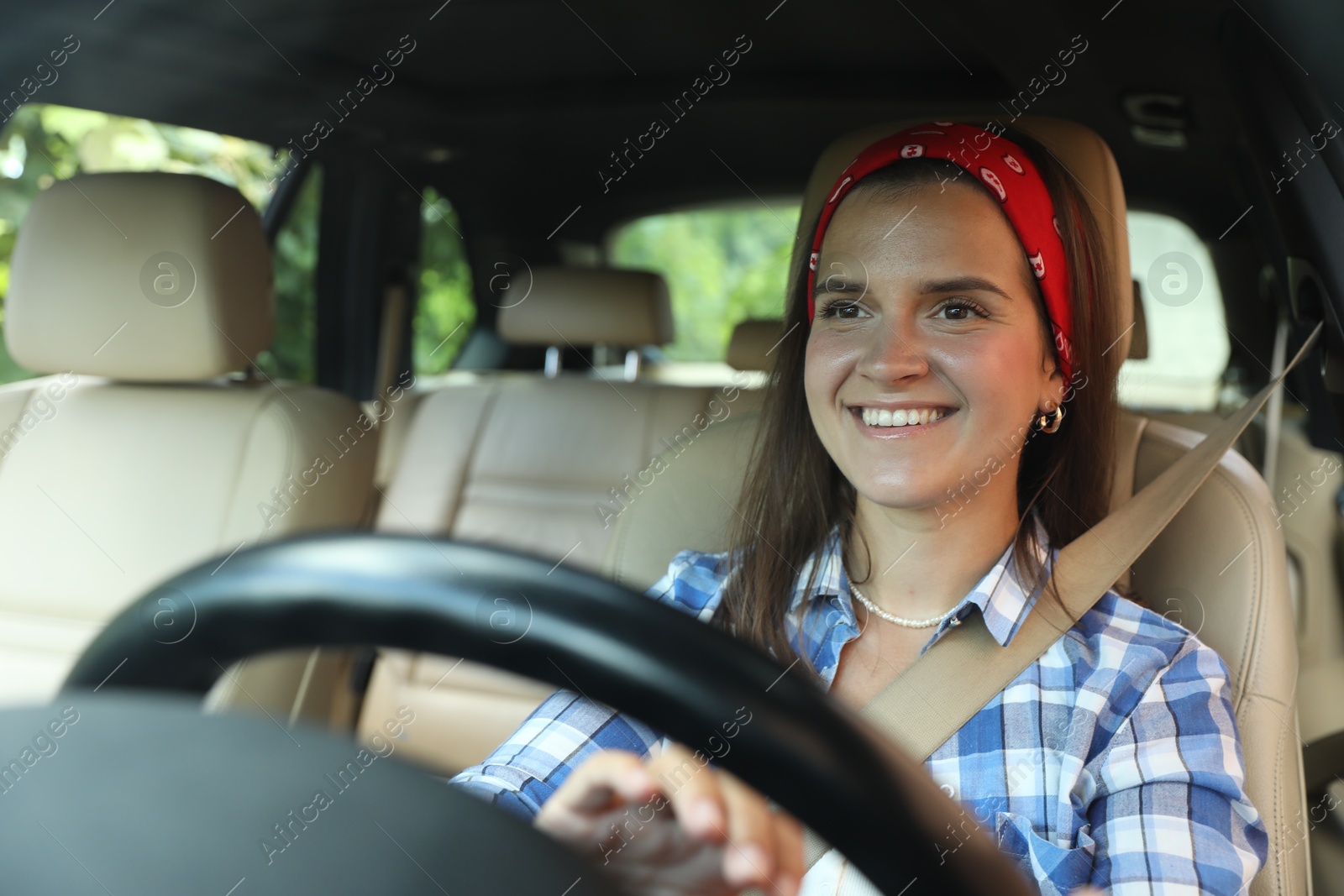 Photo of Smiling woman holding steering wheel while driving car, view from through windshield