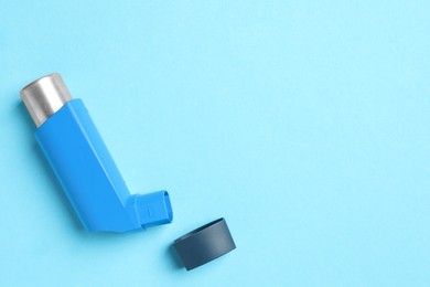 Photo of Asthma inhaler on light blue background, top view. Space for text