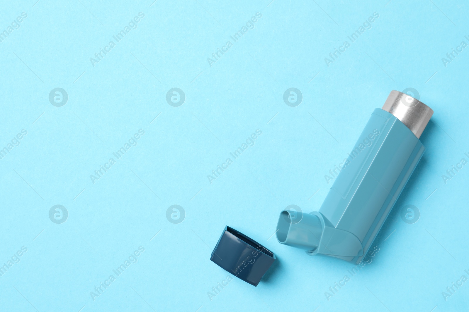 Photo of Asthma inhaler on light blue background, top view. Space for text