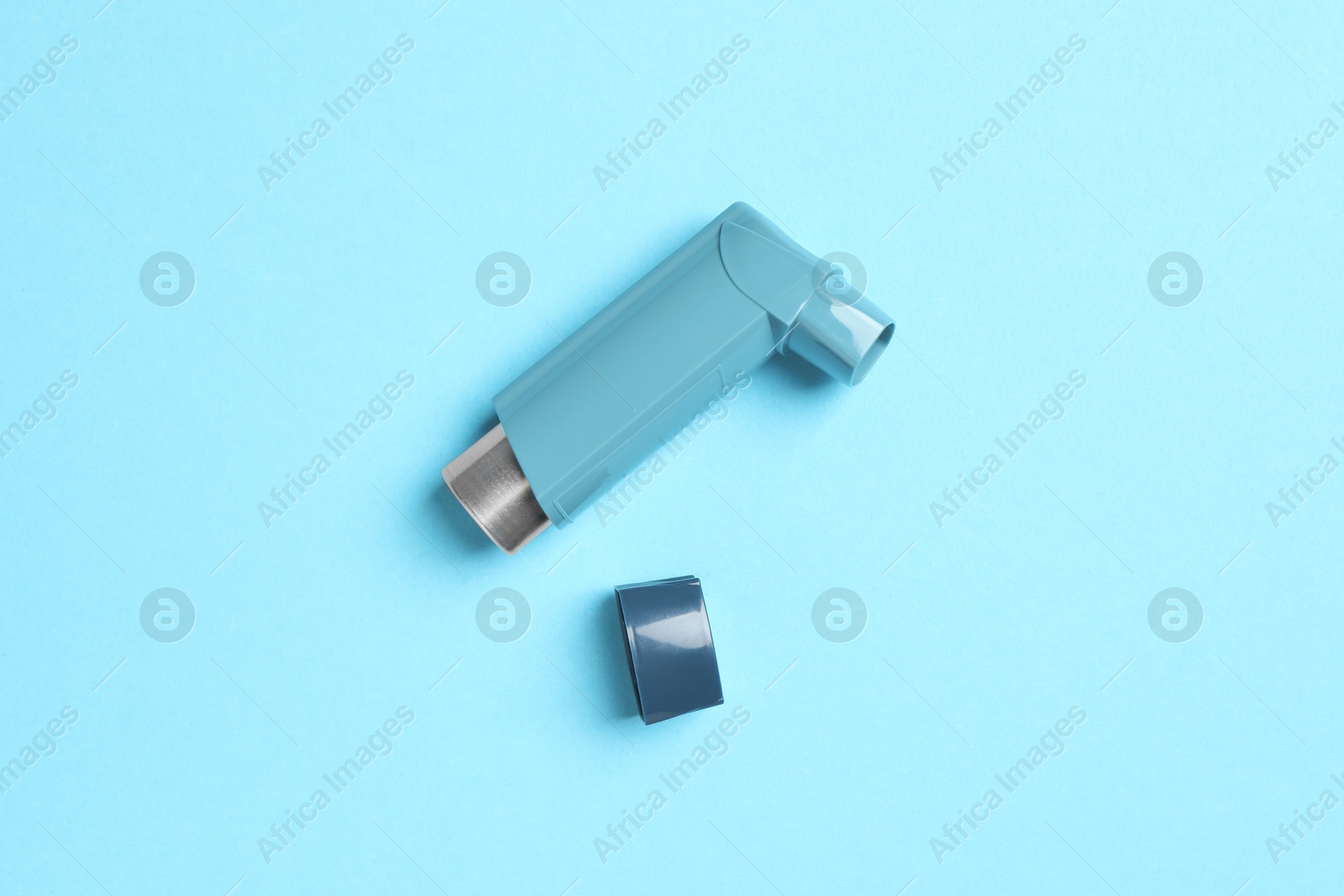 Photo of Asthma inhaler on light blue background, top view