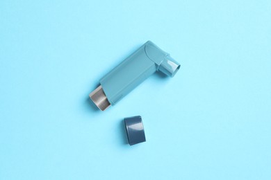 Asthma inhaler on light blue background, top view