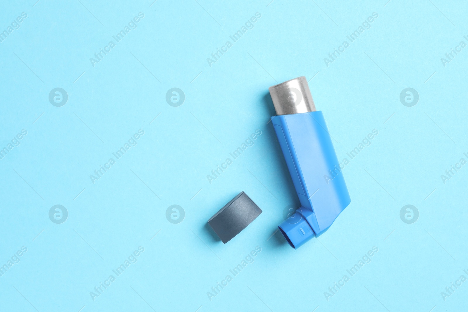 Photo of Asthma inhaler on light blue background, top view. Space for text